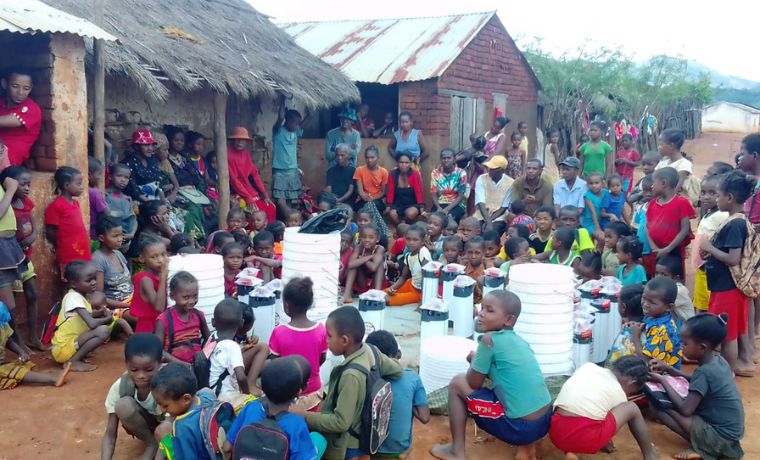 Distribution de purificateurs d’eau ORISA dans une communauté villageoise à madagascar, entourée d’enfants et de familles réunis autour du matériel distribuée par Un Enfant par la Main