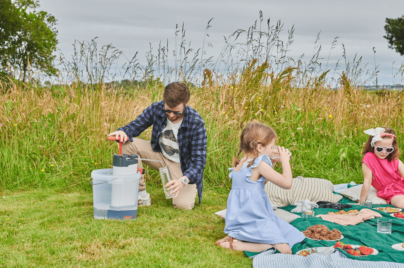 Petites filles et leur papa en pique nique avec le purificateur d'eau ORISA pour boire l'eau du lac