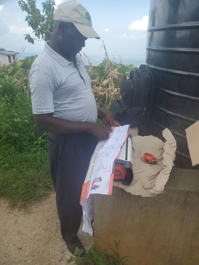 Photo d'un bénéficiaire lisant la notice, le mode d'emploi du purificateur d'eau ORISA à Haïti