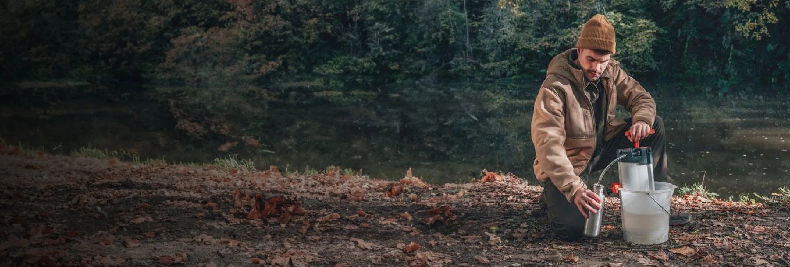 un homme utilise le purificateur d'eau orisa dans une foret pour filtrer l'eau