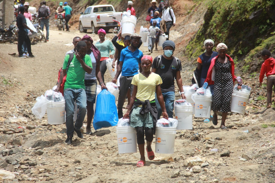 Communauté portant des purificateurs d'eau ORISA dans des seaux
