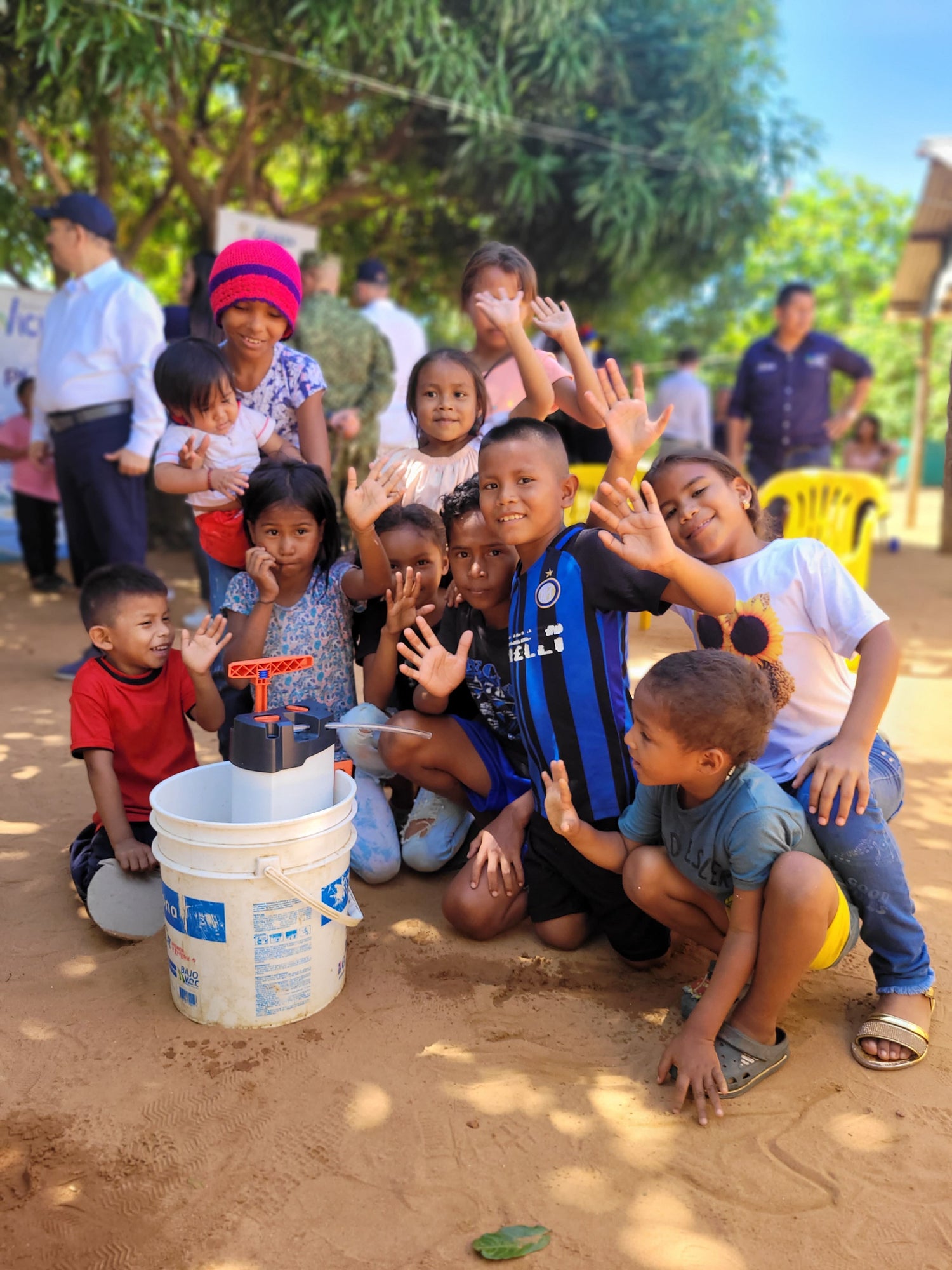 Enfants colombien qui sourient et font coucou derrière un purificateur d'eau ORISA ans un seau dans le cadre d'un déploiement