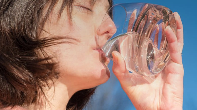 une femme boit de l'eau filtrer par le purificateur d'eau orisa