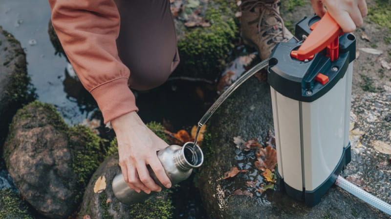 filtration d'eau dans une gourde par une randonneuse avec le purificateur d'eau orisa
