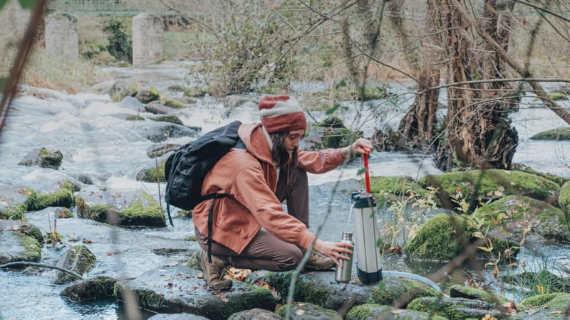 une femme en randonnée filtre d'eau d'une rivière avec le filtre à eau orisa