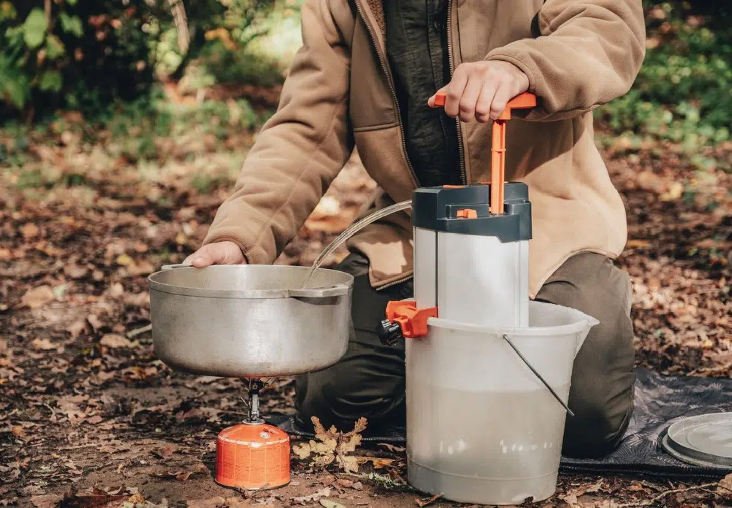 un homme filtre l'eau pour faire la cuisine avec un rechaud dans une foret