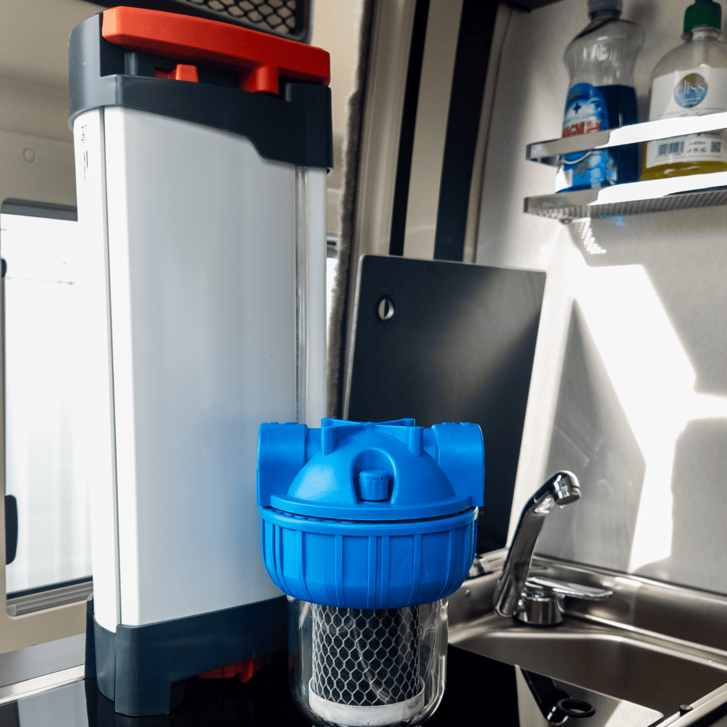 Purificateur d’eau ORISA avec porte filtre à charbon actif, installé sur le plan de travail d’un van, près de l’évier