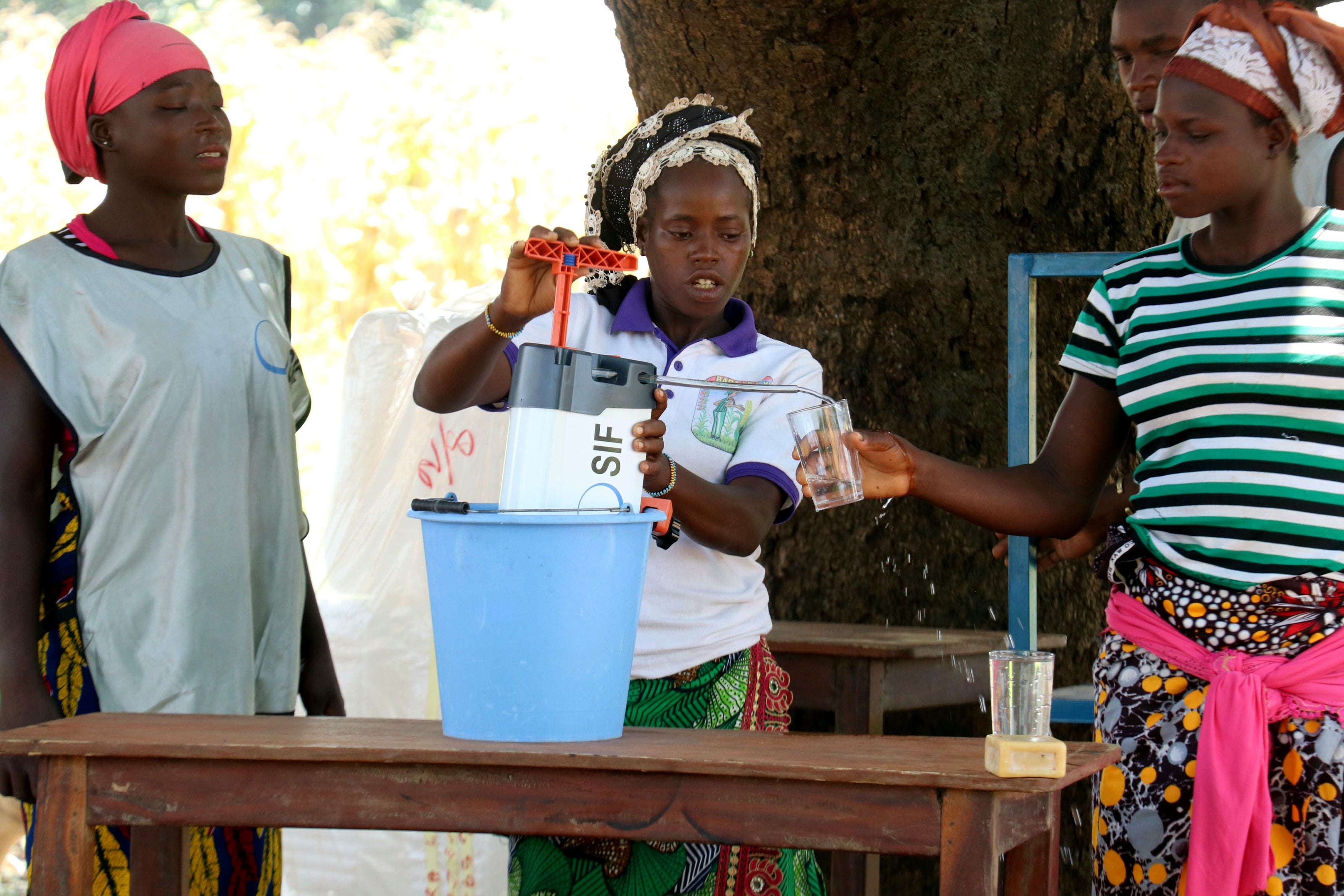 Des bénéficiaires du filtre à eau ORISA filtrent de l'eau sous le regard des équipes du Secours Islamique France