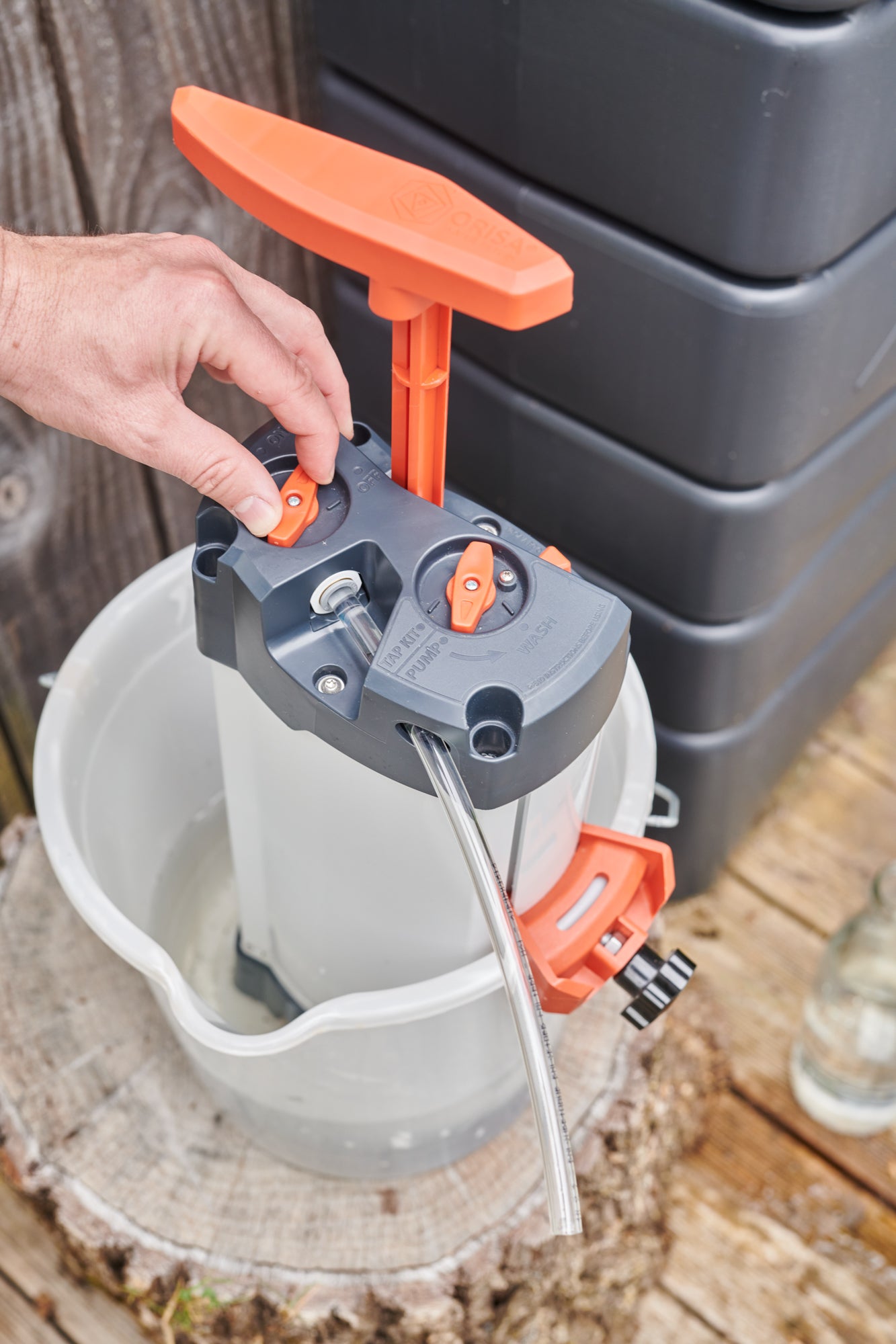 Gros plan sur un utilisateur manipulant le purificateur d’eau ORISA, positionné dans un seau en extérieur devant un récupérateur d'eau