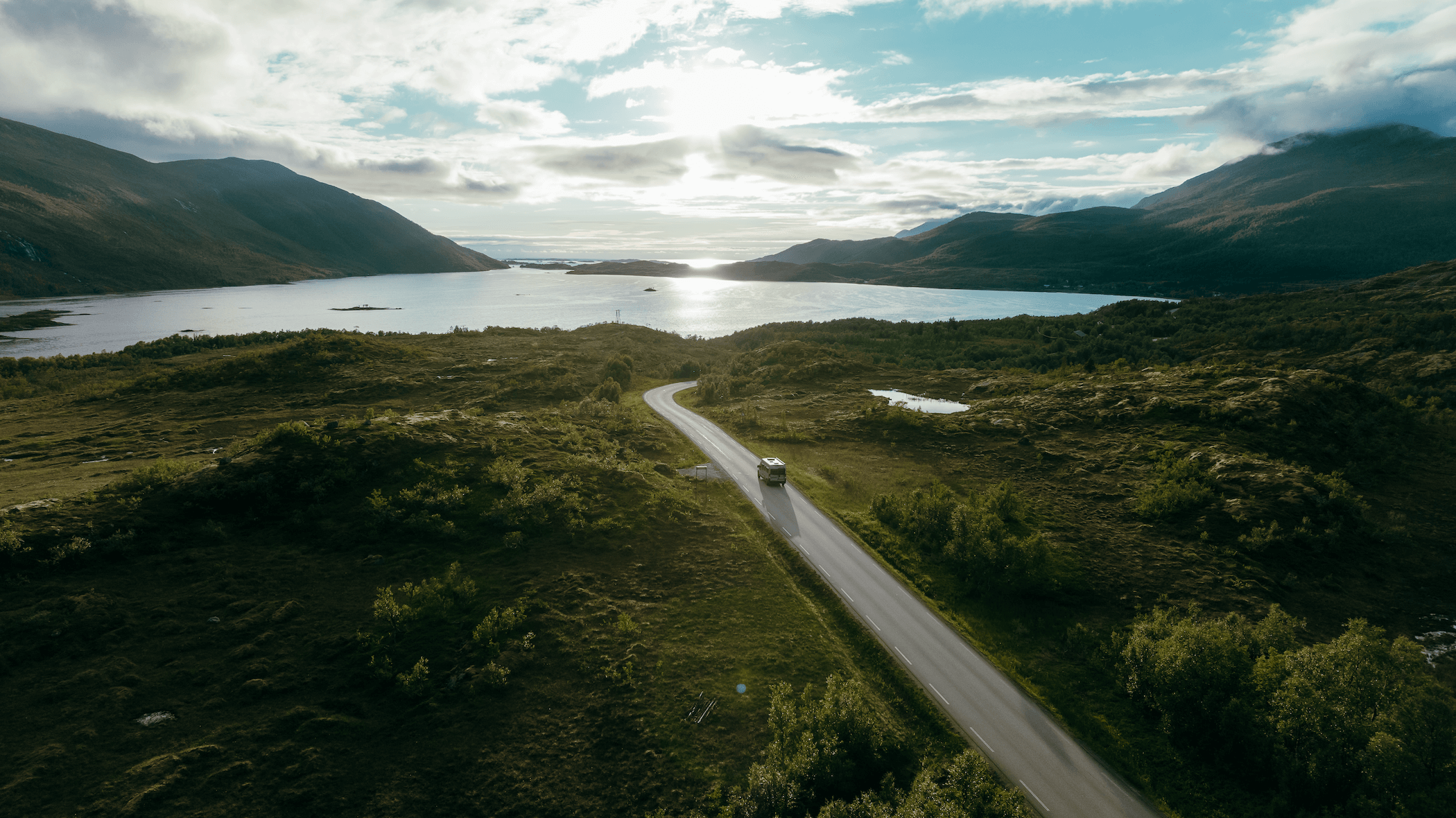 un van sur une route près d'un lac dans les iles lofoten