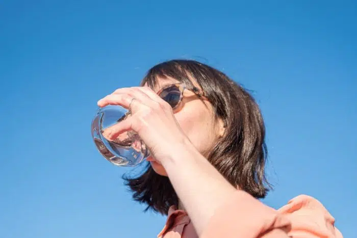 une femme boit un verre d'eau filtrer par le filtre à eau orisa