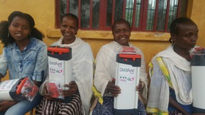 des femmes ethiopiennes sourient avec des filtres a eau orisa sur les genoux